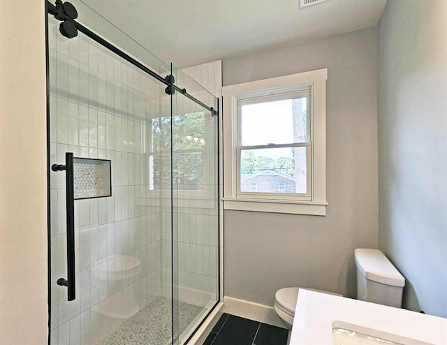 bathroom featuring toilet, tile patterned flooring, a stall shower, and baseboards