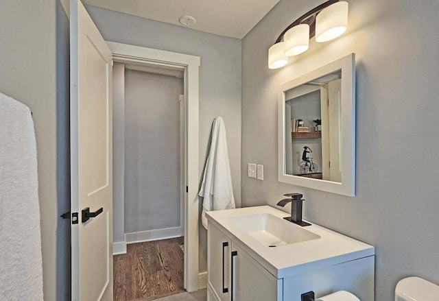 bathroom with wood finished floors, toilet, and vanity