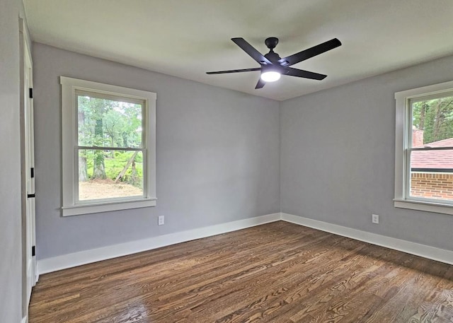 empty room featuring dark wood finished floors, baseboards, and a ceiling fan