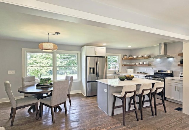 kitchen featuring a sink, decorative backsplash, wall chimney exhaust hood, baseboards, and appliances with stainless steel finishes