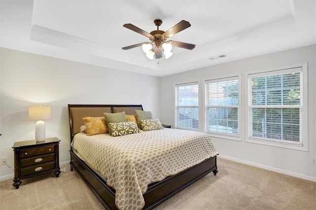 bedroom with ceiling fan, light carpet, and a tray ceiling