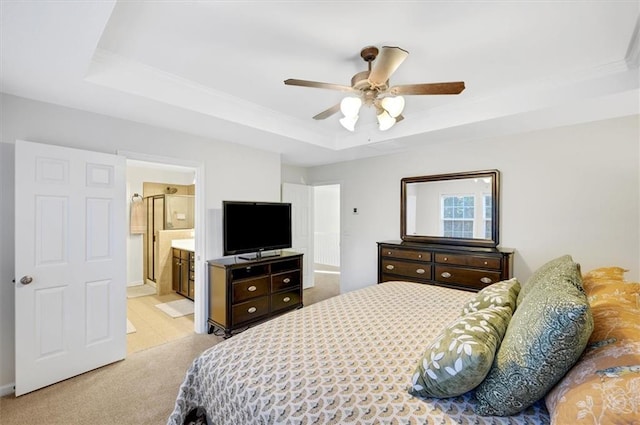 carpeted bedroom featuring a tray ceiling, ensuite bath, ceiling fan, and crown molding