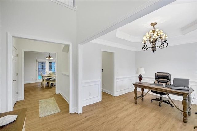 home office with a raised ceiling, light wood-type flooring, ornamental molding, and a chandelier