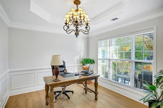 office area featuring ornamental molding, light wood-type flooring, a raised ceiling, and a notable chandelier