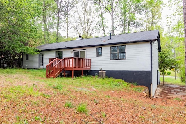 rear view of property with central AC unit, a lawn, and a wooden deck