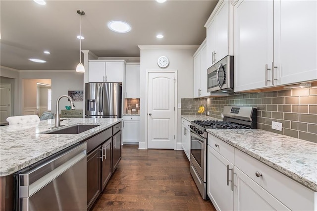 kitchen with ornamental molding, appliances with stainless steel finishes, a sink, and white cabinets