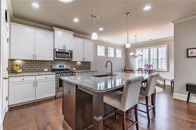 kitchen featuring visible vents, dark wood-style floors, appliances with stainless steel finishes, ornamental molding, and a sink