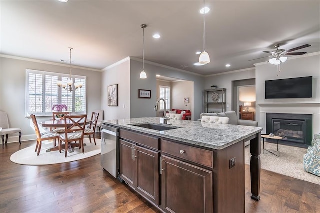 kitchen featuring a glass covered fireplace, dark wood-style flooring, a sink, pendant lighting, and stainless steel dishwasher