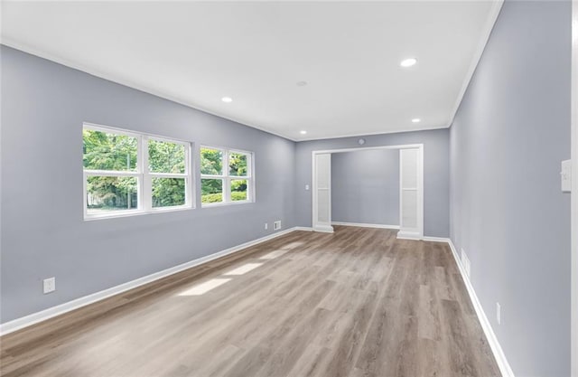 empty room featuring recessed lighting, crown molding, light wood-style flooring, and baseboards