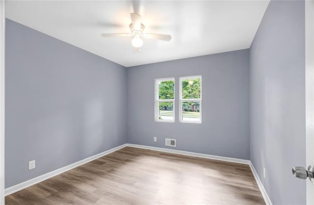 spare room featuring a ceiling fan, wood finished floors, visible vents, and baseboards