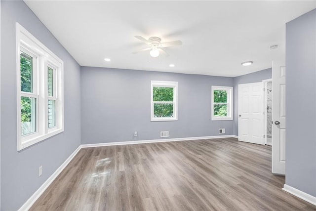 spare room with wood finished floors, visible vents, and baseboards