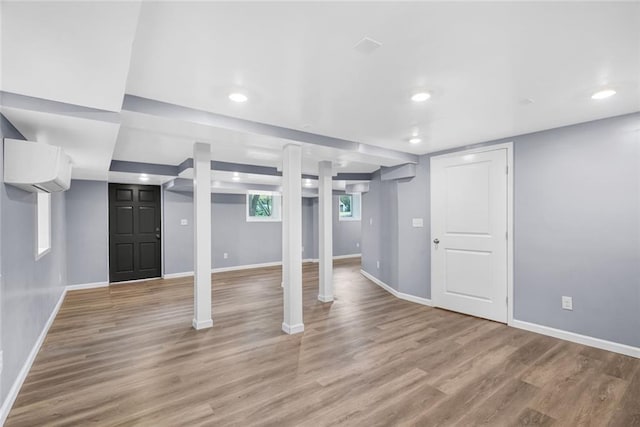 below grade area with recessed lighting, a wall unit AC, baseboards, and wood finished floors