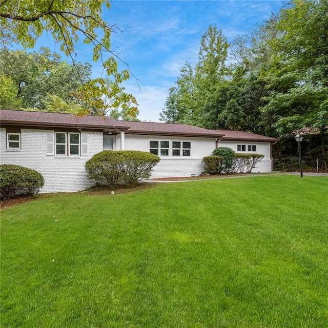 rear view of property with a lawn and brick siding