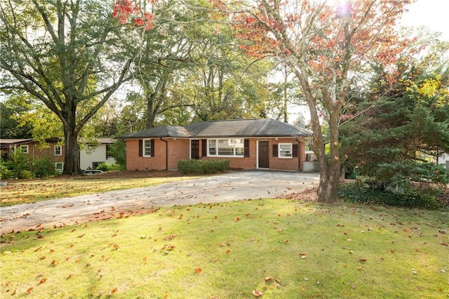 ranch-style home with brick siding, concrete driveway, and a front lawn