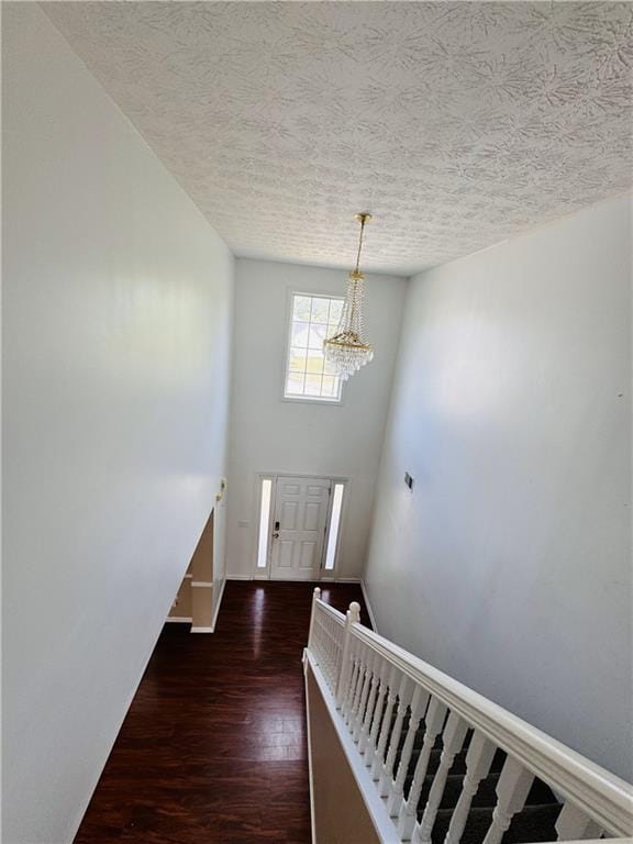 stairway with a chandelier, a textured ceiling, and hardwood / wood-style floors