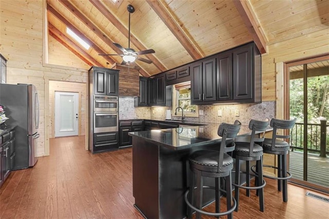 1102 Soque Wilderness Rd, Clarkesville, GA 30523 - kitchen featuring appliances with stainless steel finishes, wood walls, a peninsula, healthy amount of natural light, and a sink