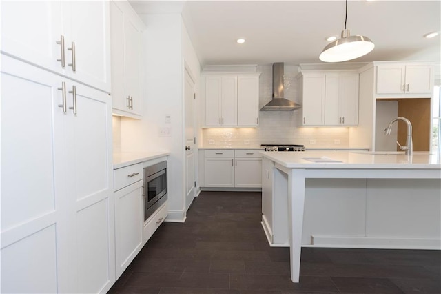 709 Dodd Ln Unit 165, Buford, GA 30518 - kitchen featuring wall chimney exhaust hood, stainless steel microwave, decorative backsplash, light countertops, and white cabinetry