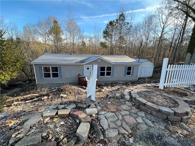 view of front of property featuring roof with shingles and fence