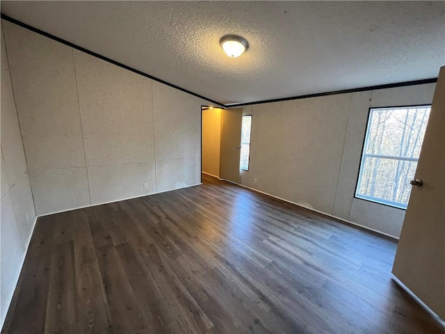 spare room with plenty of natural light, ornamental molding, a textured ceiling, and wood finished floors