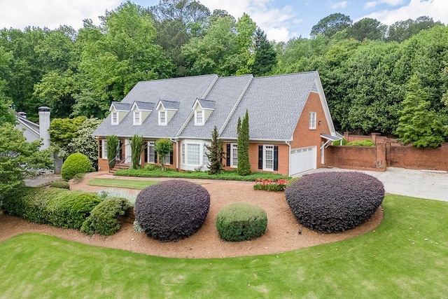 new england style home with a porch, fence, brick siding, driveway, and a front lawn