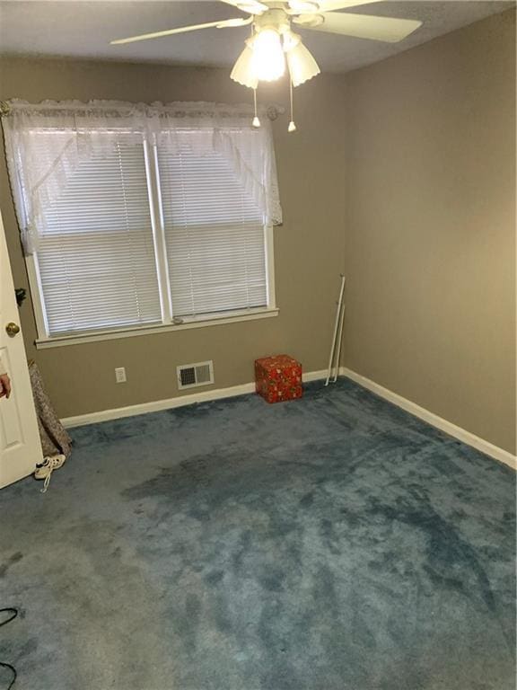 spare room featuring dark colored carpet and ceiling fan