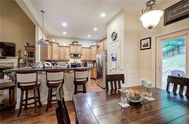 dining room featuring crown molding, wood finished floors, and a wainscoted wall