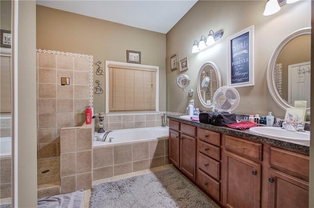 full bath featuring a garden tub, double vanity, and tiled shower