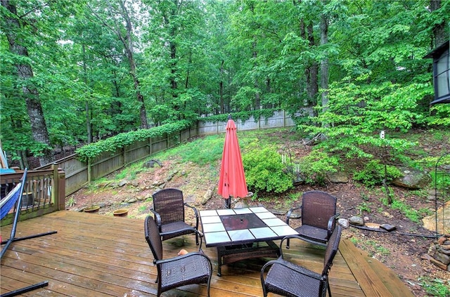 wooden terrace featuring outdoor dining space and a fenced backyard
