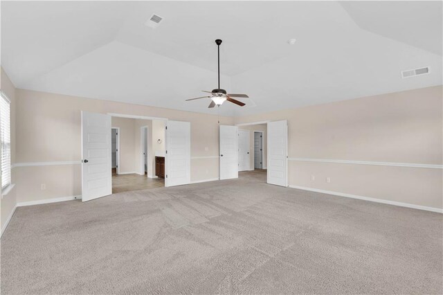 unfurnished bedroom featuring baseboards, vaulted ceiling, light colored carpet, and visible vents