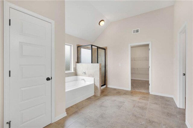 bathroom featuring a walk in closet, visible vents, a shower stall, vaulted ceiling, and a bath