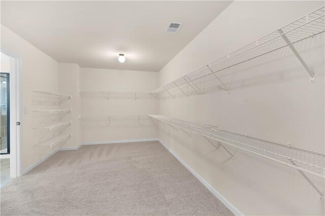 spacious closet featuring light colored carpet and visible vents