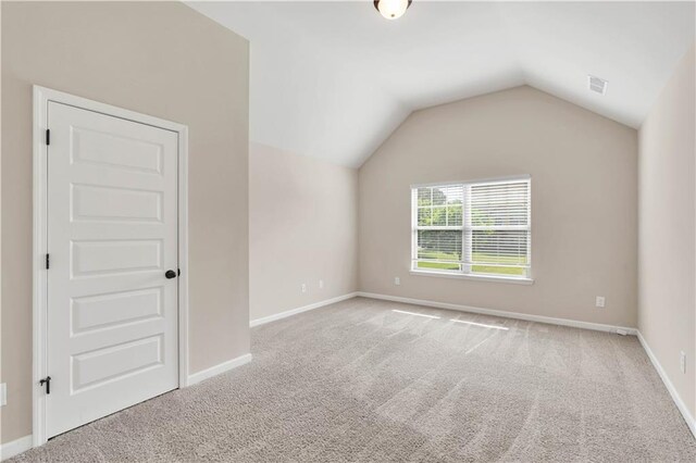 additional living space with baseboards, visible vents, carpet, and lofted ceiling