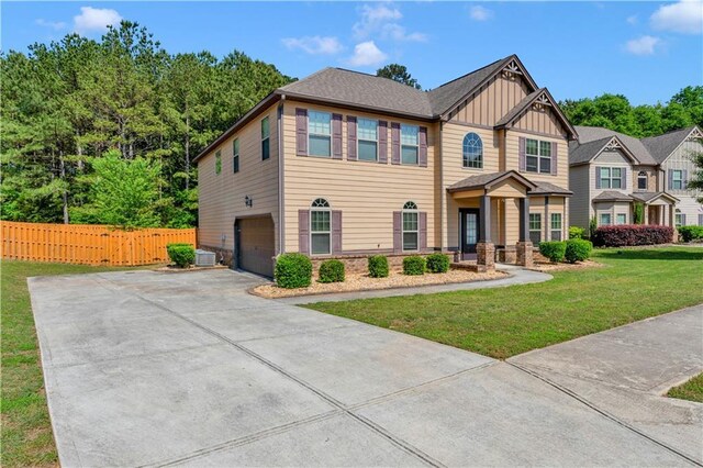 craftsman-style home with a front lawn, fence, board and batten siding, concrete driveway, and an attached garage