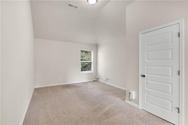 carpeted empty room with baseboards, high vaulted ceiling, and visible vents