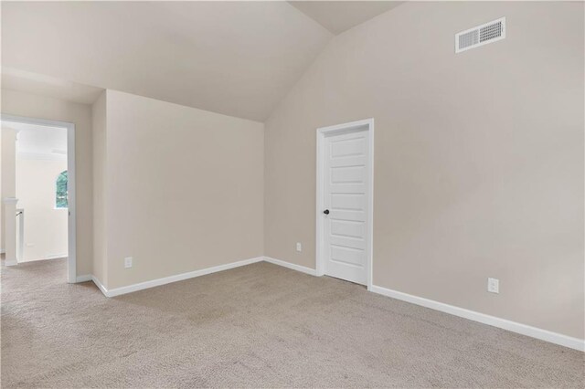 carpeted spare room featuring baseboards, visible vents, and lofted ceiling