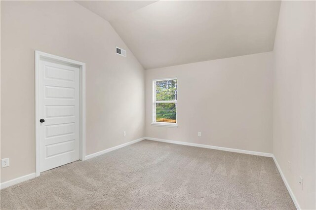 empty room with baseboards, visible vents, carpet, and lofted ceiling