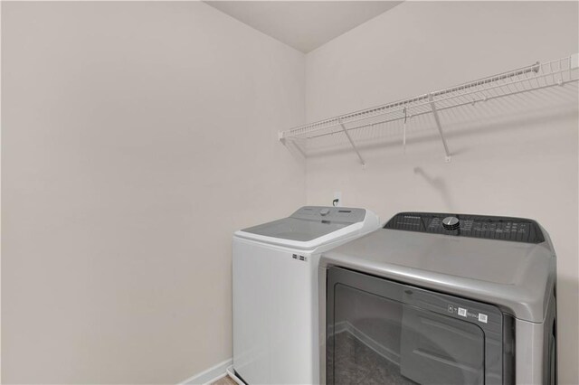 washroom featuring separate washer and dryer, baseboards, and laundry area