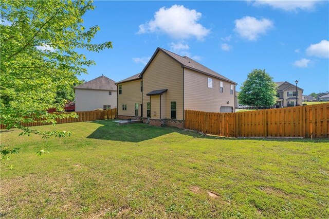 rear view of property featuring a lawn and a fenced backyard