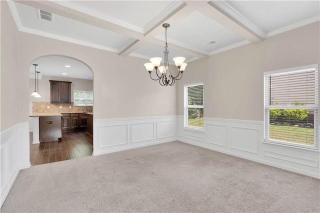 unfurnished dining area with visible vents, beam ceiling, a wainscoted wall, a chandelier, and dark carpet