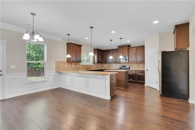 kitchen featuring appliances with stainless steel finishes, decorative backsplash, light stone countertops, and a peninsula
