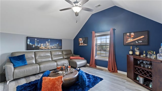 living room with ceiling fan, vaulted ceiling, indoor bar, and light wood-type flooring