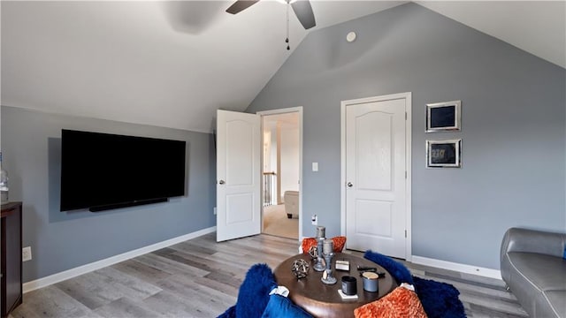 living room with ceiling fan, vaulted ceiling, and light hardwood / wood-style flooring