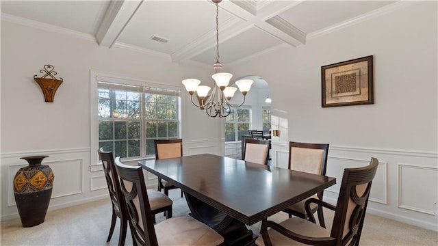 dining space featuring an inviting chandelier, ornamental molding, light colored carpet, and beamed ceiling