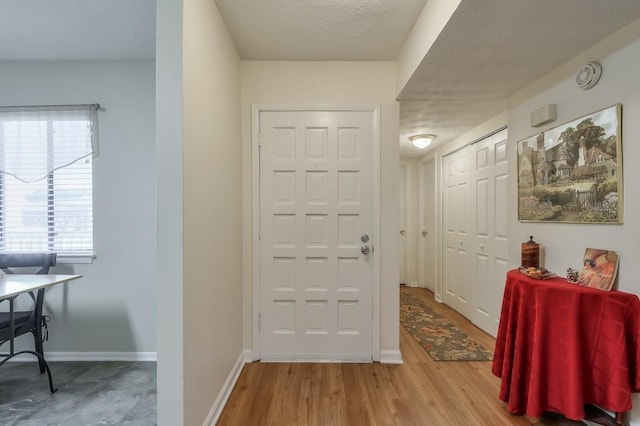 entryway with baseboards, wood finished floors, and a textured ceiling