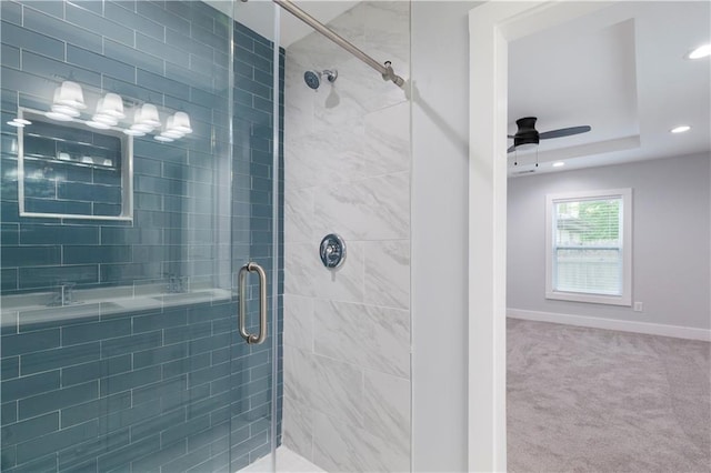 bathroom featuring ceiling fan, a tray ceiling, and walk in shower