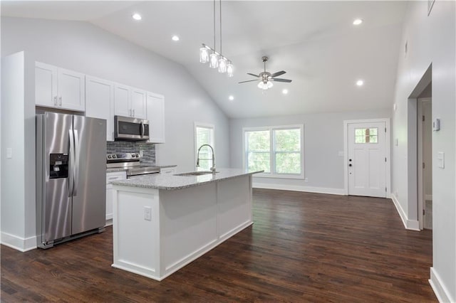 kitchen with white cabinets, appliances with stainless steel finishes, decorative backsplash, sink, and a center island with sink