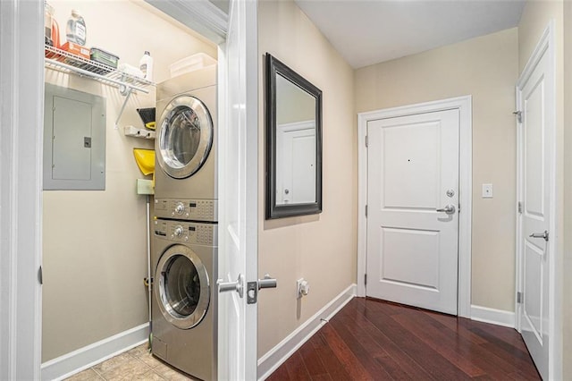 laundry area featuring electric panel, estacked washer and dryer, baseboards, and wood finished floors