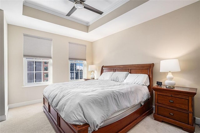 bedroom featuring light colored carpet, a tray ceiling, ornamental molding, baseboards, and ceiling fan