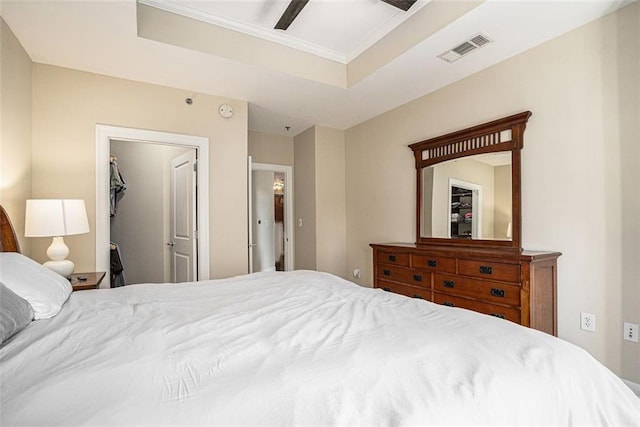 bedroom featuring a raised ceiling, crown molding, a ceiling fan, and a spacious closet