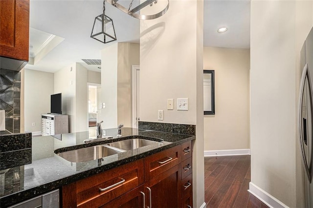 kitchen featuring a sink, dark stone counters, baseboards, and dark wood-type flooring